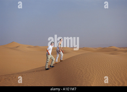 Giovane uomo e donna a piedi fino le dune di sabbia del deserto del Sahara in Marocco Foto Stock