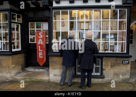 Coppia di anziani guardare nella vetrina di un negozio di merceria Burford Oxfordshire UK Foto Stock