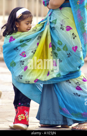 Giovani indiani bambino kid ragazza camminare avvolto in seta sari di sua madre donna al Qutb Minar a Nuova Delhi, India Foto Stock