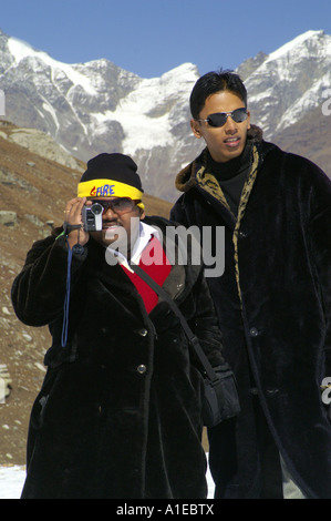 Indiano Fat Man in Black pelliccia con la macchina fotografica del film sul bianco della neve in Rohtang Pass, Himalaya indiano Foto Stock