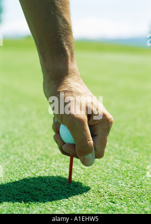 L'uomo posizionando la pallina da golf sul raccordo a T Foto Stock