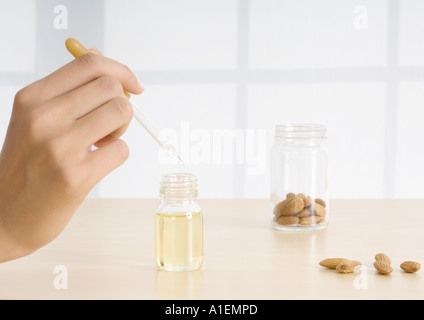 Donna di mano azienda dropper di olio essenziale con le mandorle Foto Stock