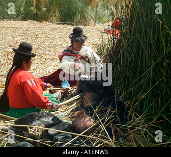 Le donne indiane la cottura su isole galleggianti di Uros sul lago Titicaca in Perù. Foto Stock