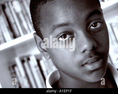 AFRICAN BOY STUDENTESSA 13-15 anni primo piano coinvolgente potente ritratto in bianco e nero di adolescente maschio studente nero in biblioteca scuola Foto Stock