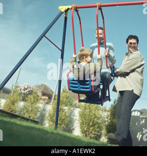 L'uomo spingendo la moglie e figlio per rotazione Foto Stock