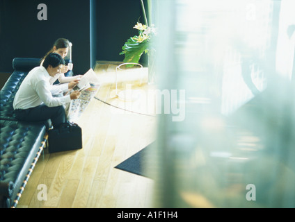 L uomo e la donna seduta sul banco di prova nella lobby, ad alto angolo di visione Foto Stock