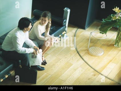 L uomo e la donna seduta sul banco di prova nella lobby, ad alto angolo di visione Foto Stock