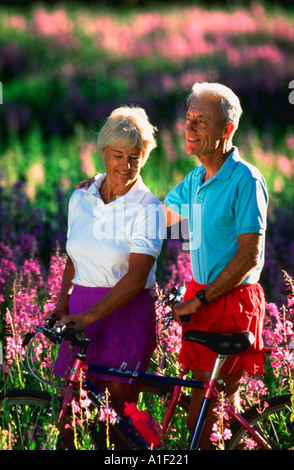 Coppia di anziani con la mountain bike in estate fiori selvatici in Albion Basin Wasatch Mountains vicino a Salt Lake City nello Utah Foto Stock