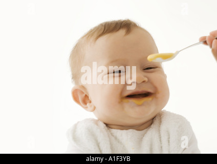 Sorridente baby essendo alimentato pappe per bambini Foto Stock