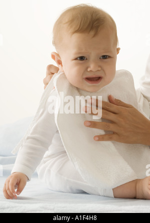 Genitore mettendo la bib su Gridando bambino, vista ritagliata Foto Stock