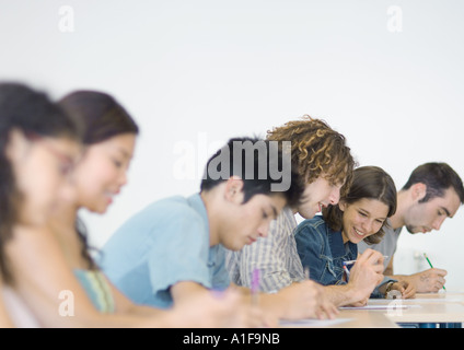 Gli studenti seduti fianco a fianco in classe, facendo il lavoro in classe Foto Stock