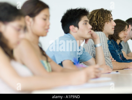 Gli studenti seduti fianco a fianco con attenzione in classe Foto Stock