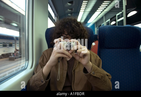 Giovane passeggero scatta foto con una piccola fotocamera digitale in una cabina ferroviaria Roma Italia Foto Stock