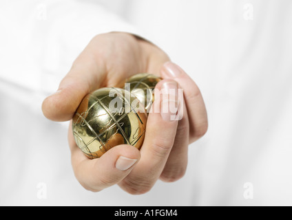 Mano che tiene le sfere metalliche Foto Stock