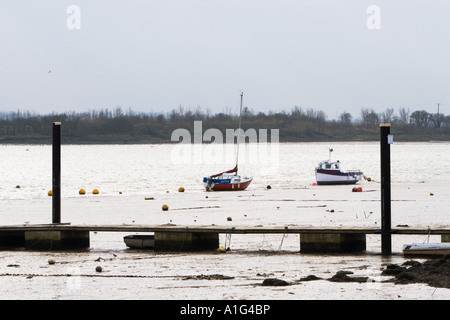 Barche a vela e il dock in fango a bassa marea sul fiume Blackwater Heybridge Basin Inghilterra Foto Stock