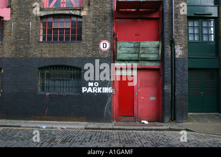 Old brick warehouse con colore rosso brillante porte a Wapping east London con nessun segno di parcheggio dipinta sulla parete Foto Stock