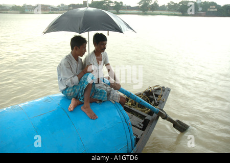 I pescatori seduti sulla barca durante la pioggia sul fiume Hoogly Kolkata India Foto Stock