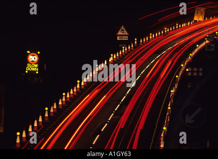 Il traffico pesante che passa a 50 mph velocità di limitazione segnale di avvertimento contraflow sulla a1 autostrada m1 nei pressi di Leeds di notte regno unito Foto Stock