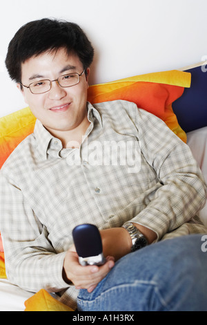 Ritratto di un giovane uomo in possesso di un telefono cellulare sorridente Foto Stock