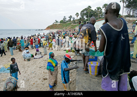 La folla si raccolgono sulla spiaggia per arrivo di barche da pesca Bakau Gambia Foto Stock