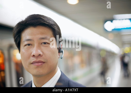 Ritratto di un imprenditore che indossa un dispositivo vivavoce a una stazione della metropolitana
