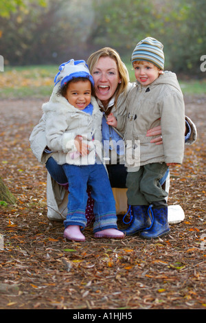 Una famiglia moderna madre e figlio e figlia divertirsi insieme in un parco verdeggiante. Foto Stock