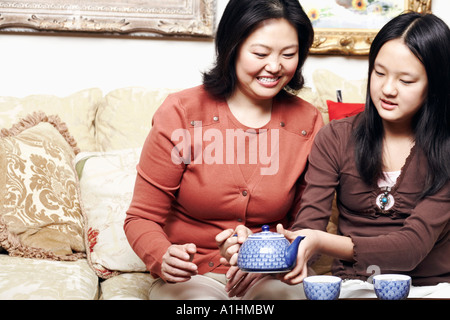 Close-up di una ragazza con una teiera seduto con sua madre Foto Stock