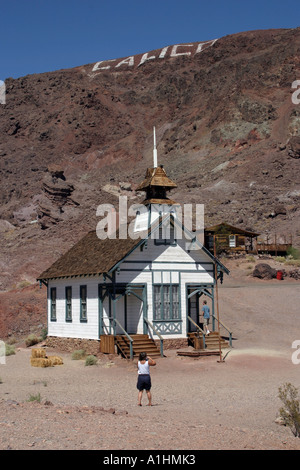 Una persona in piedi guardando la old school house,Calico argento vecchio borgo minerario California USA con nome inciso in Hillside Foto Stock