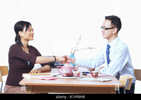 Imprenditore e imprenditrice seduti su sedie stringono le mani Foto Stock