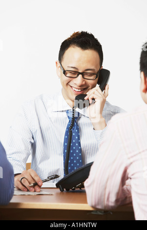 Close-up di un imprenditore parlando al telefono con due imprenditori seduto di fronte a lui Foto Stock