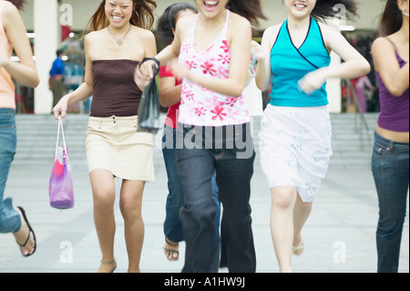 Metà vista in sezione di un gruppo di giovani donne in esecuzione con le borse della spesa Foto Stock