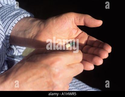 Mani di un paziente di sesso maschile in un accappatoio prendendo una pillola Foto Stock