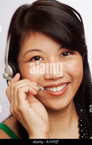 Ritratto di una giovane donna sorridente e indossare un auricolare Foto Stock