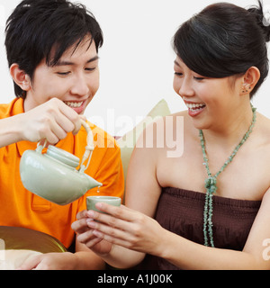 Close-up di un giovane uomo di versare il caffè in una tazza detenute da una giovane donna Foto Stock