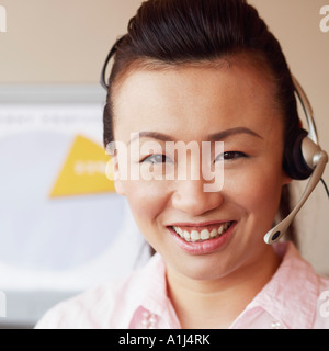 Ritratto di una donna rappresentante del servizio clienti parlando su un auricolare e sorridente Foto Stock