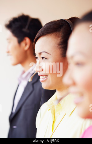 Il profilo laterale di una femmina di rappresentante del servizio clienti sorridente con due colleghi Foto Stock