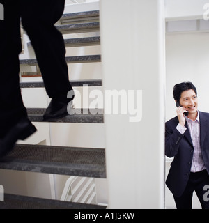 Bassa vista in sezione di un uomo a piedi giù per le scale con un altro imprenditore a parlare su un telefono mobile Foto Stock