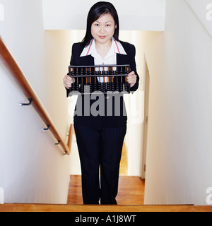 Ritratto di una imprenditrice tenendo un abaco e stando in piedi sulla scala Foto Stock