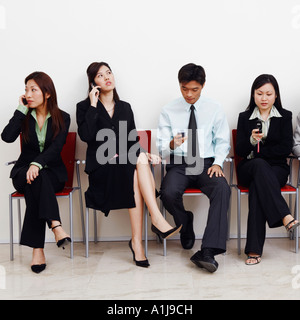 Due imprenditori e tre imprenditrici seduto con i telefoni cellulari Foto Stock