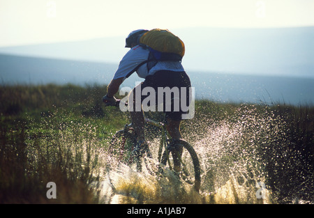 L'uomo mountain bike attraverso acqua con splash Foto Stock