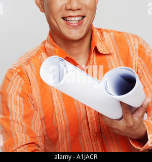 Ritratto di un architetto maschio tenendo due blueprint e sorridente Foto Stock