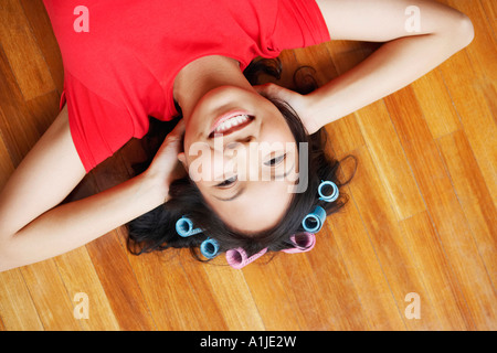Ritratto di una giovane donna sdraiata su un pavimento di legno duro e sorridente Foto Stock