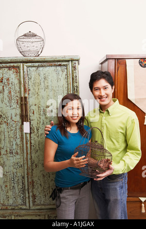 Ritratto di una giovane coppia tenendo una gabbia e sorridente Foto Stock