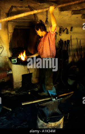 Un fabbro opere il soffietto alla fucina di acciaio nel negozio di fabbro ferraio a El Rancho de Las Golondrinas vicino a Santa Fe New Mexico Foto Stock