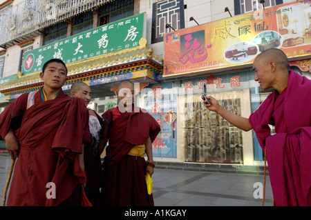 Un monaco prende una foto dei suoi compagni con un telefono cellulare in una strada dello shopping a Lhasa il Tibet Ottobre 19 2006 Foto Stock