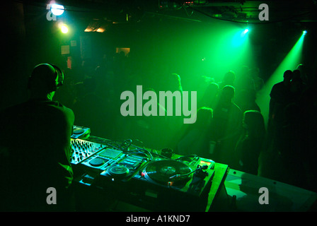 Discoteca DJ giocare una serie in un affollato Locale notturno Foto Stock