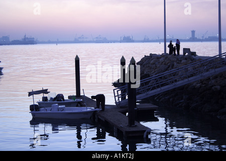 Silhouette di persone fishin in Kuwait Kuwait porto di famiglia in piedi sulla piattaforma Kuwait City Foto Stock