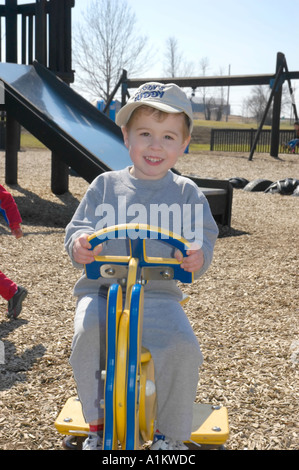 Giovani sorridente tre anno vecchio ragazzo su un sedile basculante presso il parco giochi Foto Stock