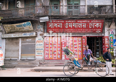 In rickshaw estrattore in appoggio sul suo rickshaw davanti a un negozio in Sonargoan Bangladesh Foto Stock