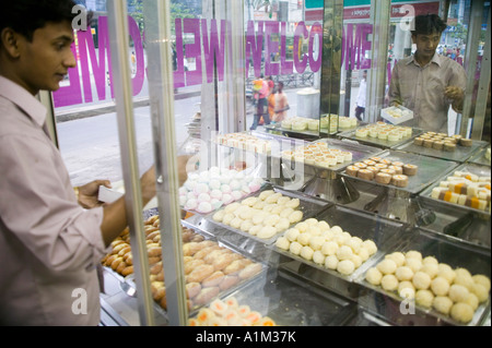 L'uomo la selezione di dolci da una panetteria a Dacca in Bangladesh Foto Stock
